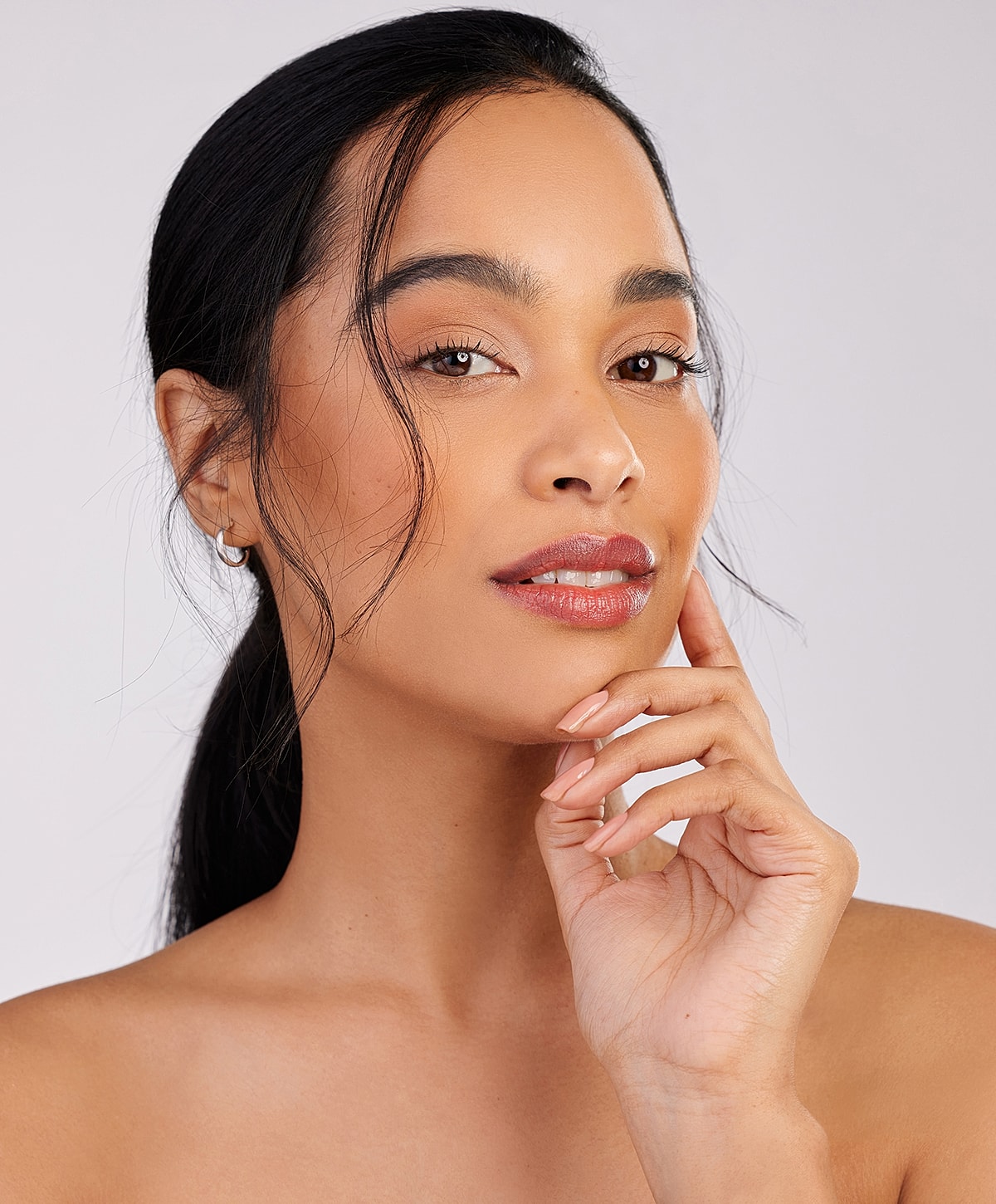 Charlotte, NC earlobe repair model with hand on chin, neutral background.