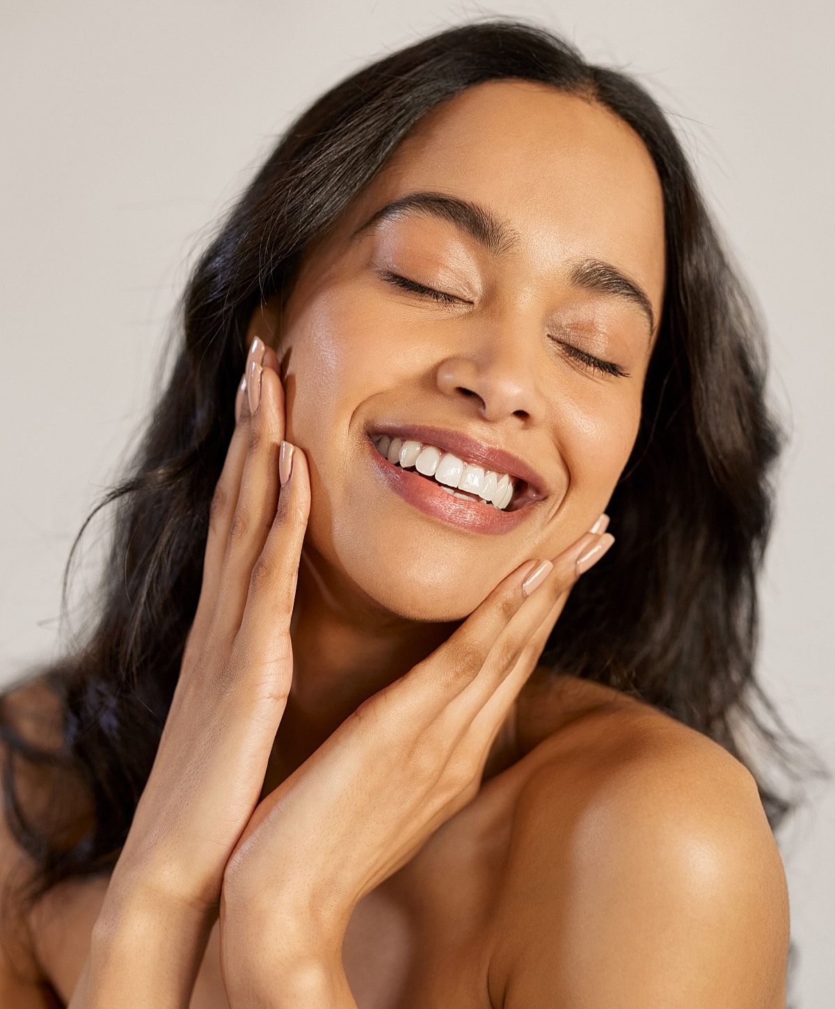 Charlotte, NC blepharoplasty model touching her face, glowing skin.