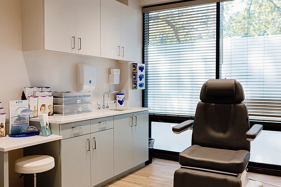 Medical office interior with examination chair and supplies.